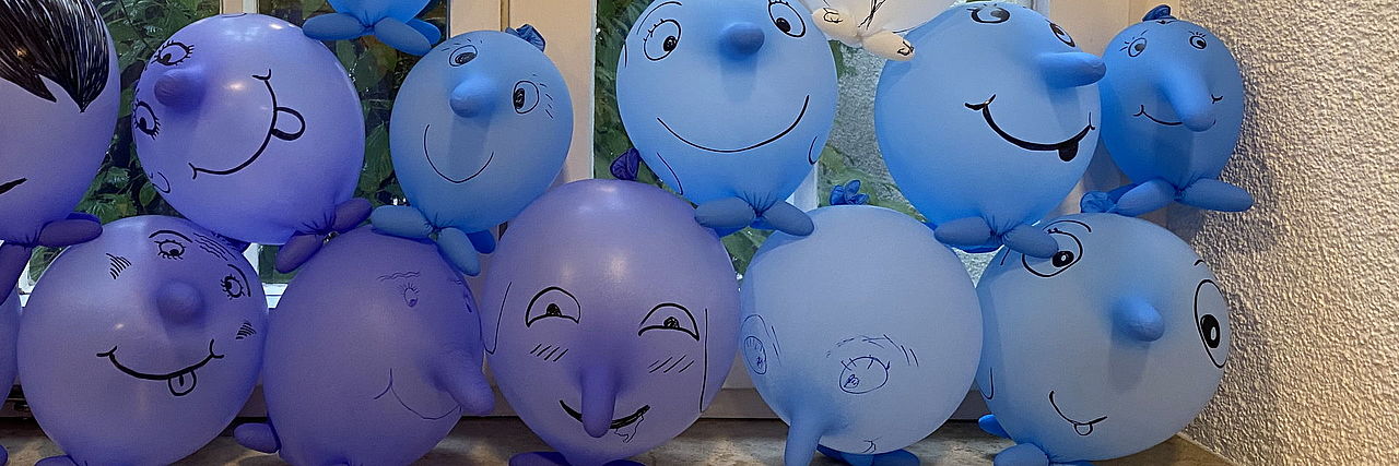 Blaue Einmal-Handschuhe, die zu Luftballons aufgepustet und bemalt sind